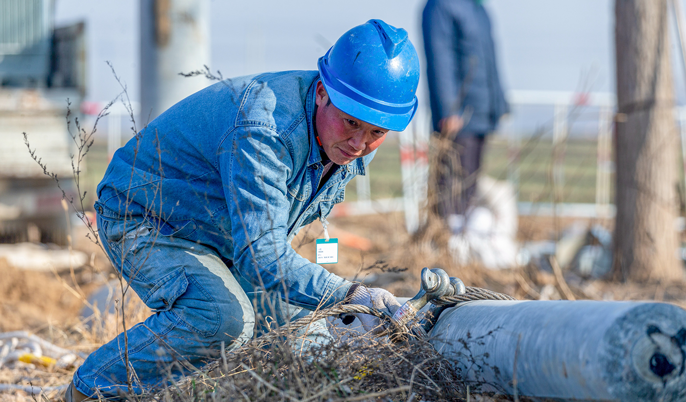 农村电气化信息网讯：（通讯员 王亚方 杨子超）2026年1月8日上午，在河南省安阳市滑县半坡店镇杏头村的农田里，国网滑县供电公司李刚、魏成亮、霍俊英等十名施工队员正紧张有序地开展杏头5号机井通电配套工程施工。图1为，2026年1月8日上午，在河南省安阳市滑县半坡店镇杏头村的农田里，杏头5号机井通电配套工程施工现场，国网滑县供电公司施工队员魏成亮正在紧锢钢丝绳，为随后的吊装电杆作业做准备。（王亚方 摄）