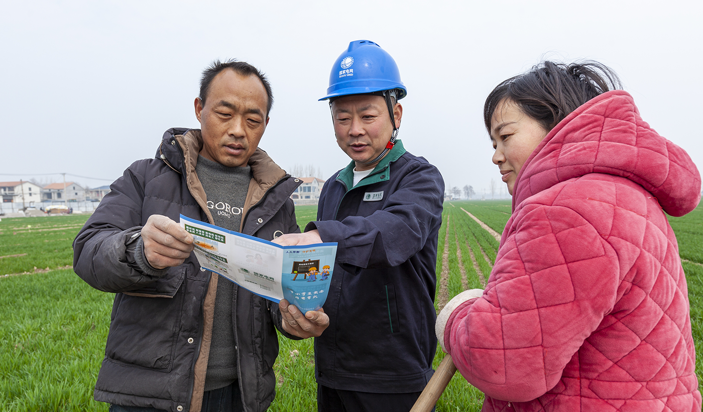 眼下正是春灌关键期，滑县供电公司组成23支电力服务队活跃在田间地头，对涉农线路设备进行“地毯式”体检。从排查闸刀线路到清理鸟巢树障，服务队把隐患消灭在萌芽状态，确保农户灌溉用电无忧。图为，2026年3月16日上午，国网滑县供电公司电力服务队队员康玉川、赵强在八里营镇东风村麦田，检查春灌用电设备并提醒村民安全用电。（王亚方 摄）